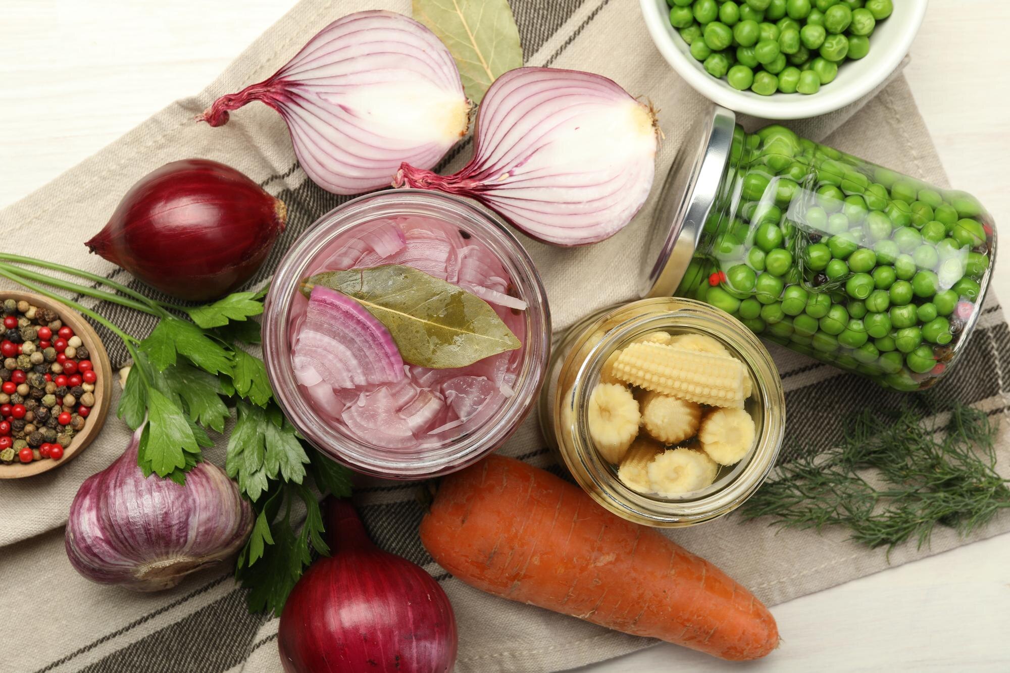 An assortment of pickled vegetables, fermented foods and fresh ingredients in jars and bowls on a white table